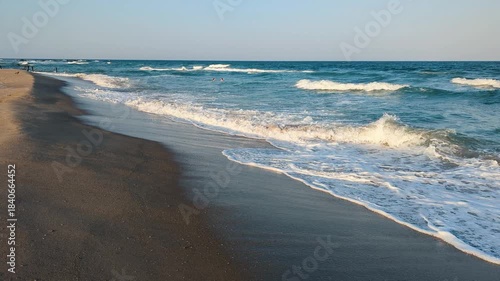 Soft waves roll onto a bright sandy shore.