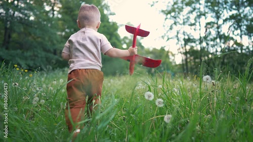 Child running in the grass. A toddler is playing in the grass outside. A toy for exploring nature in summer. A child is sprinting through the grass lifestyle.