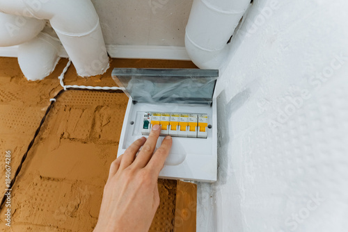 electrical switch operation, focus on grip and electrical control during maintenance activity, person manually activating circuit breaker for safety purposes through fingertip toggle switch