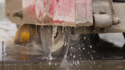 Cutting concrete with an industrial diamond floor saw. Close-up of an industrial concrete saw cutting wet concrete at a construction site. The diamond blade is cooled with water.