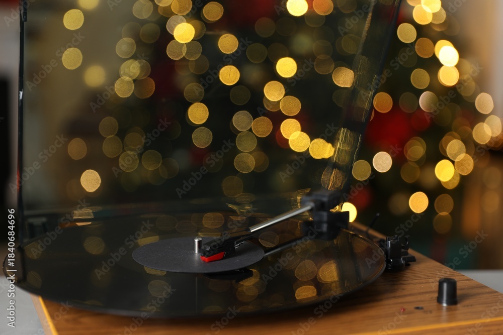 Naklejka premium Turntable with vinyl record on table near Christmas tree, closeup