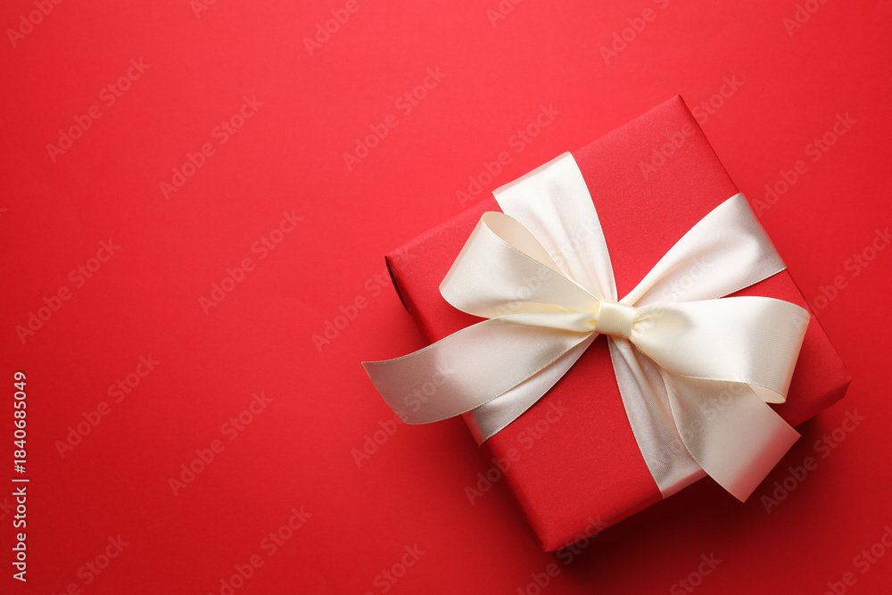 Fototapeta premium Beautiful gift with bow on red background, top view