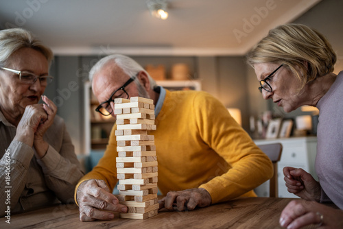 Seniors playing jenga game with friends at home