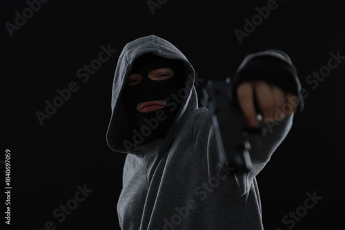 Photography Criminal man in mask with gun on black background
