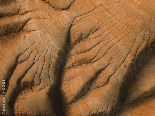 Aerial view of rugged, parched earth etched with deep gullies and ridges, showcasing nature's raw artistry in warm earthy tones, Centuripe, Sicilia, Italy.