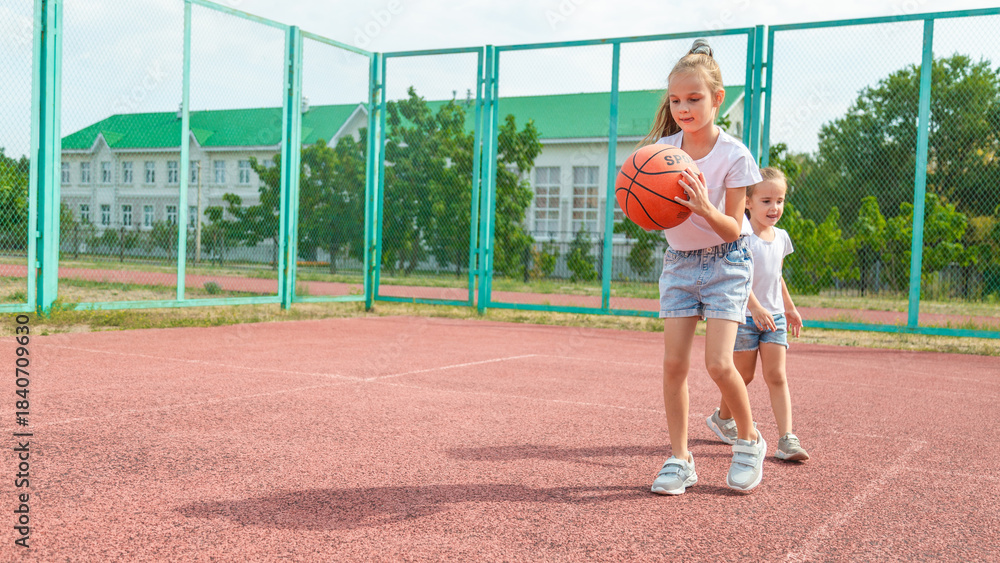 Fototapeta premium summer vacation, sport, games and friendship concept - happy children playing basketball outdoors