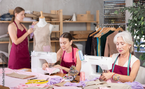 Tableau sur toile Female dressmakers work in a workshop, a fashion designer stands near a mannequi