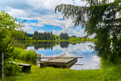Schöner Teich mit Floß in der Nähe der Ortschaft “Seeg im Allgäu“, Bayern, Deutschland.