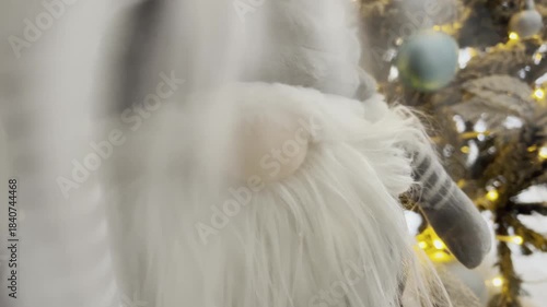 Gray festive gnomes against the background of a bright glowing Christmas tree.