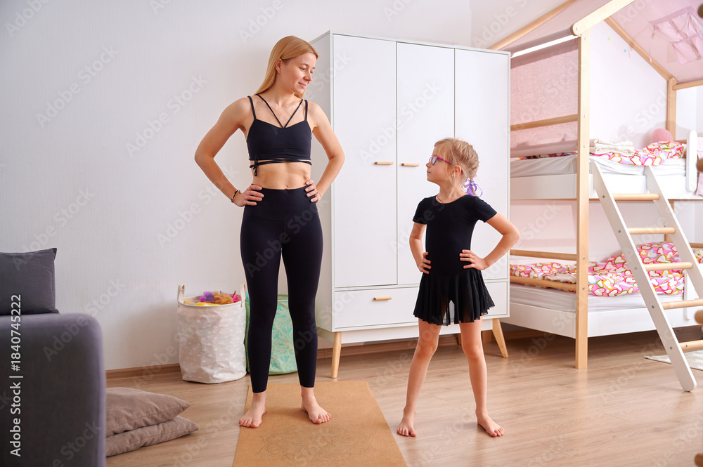 Fototapeta premium Mother and daughter practicing yoga at home