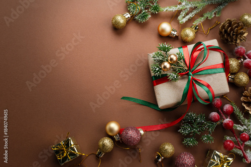 Christmas background with handmade gift box with bow, decorative fir branch, ball and cones for tree decoraton. New Year winter holiday ornaments, presents, decor and copy space for text, top view.