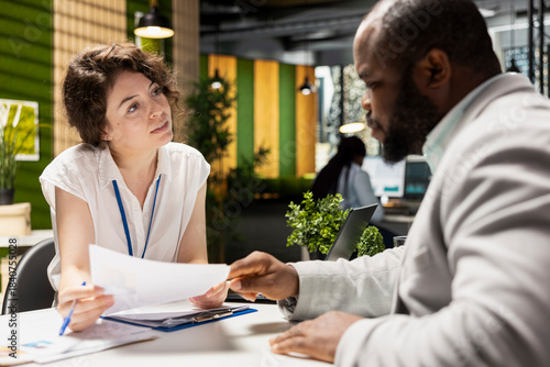 Quadro em tela Female HR recruiter speaking with black man job seeker in office, discussing CV resume feedback during formal interview, asking questions to ensure a successful meeting for career development