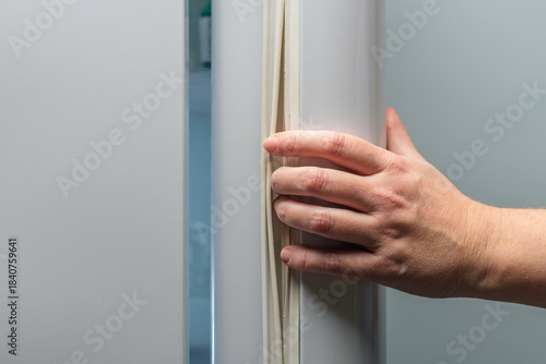 Foto Hand pulls refrigerator door by rubber gasket, demonstrating wrong way to open f