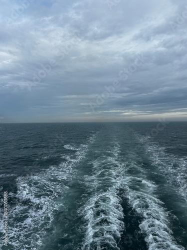 Heckwelle hinter einem Kreuzfahrtschiff bei dramatischem Wolkenhimmel