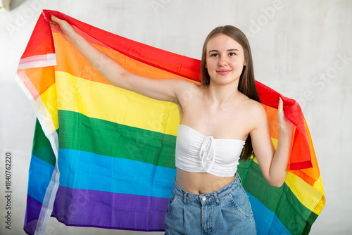 Portrait of a playful girl holding an LGBT flag in her hands