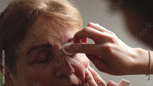 One hand of a cosmetologist paints the eyebrows of an elderly woman.