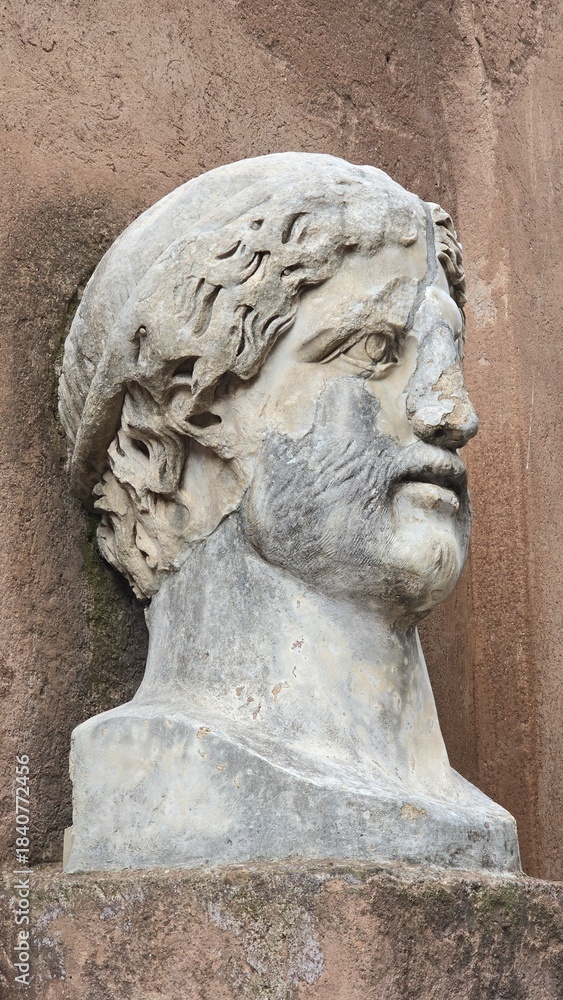 Obraz premium Rome, Italy - 12 January 2025. Worn marble head sculpture with beard and chiseled hair mounted on an exterior wall of Castel Sant’Angelo.