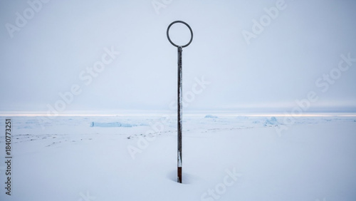 A solitary weathered metal pole with a circular top stands firmly planted in deep snow on a vast frozen landscape with ice formations in the distance isolated on white background