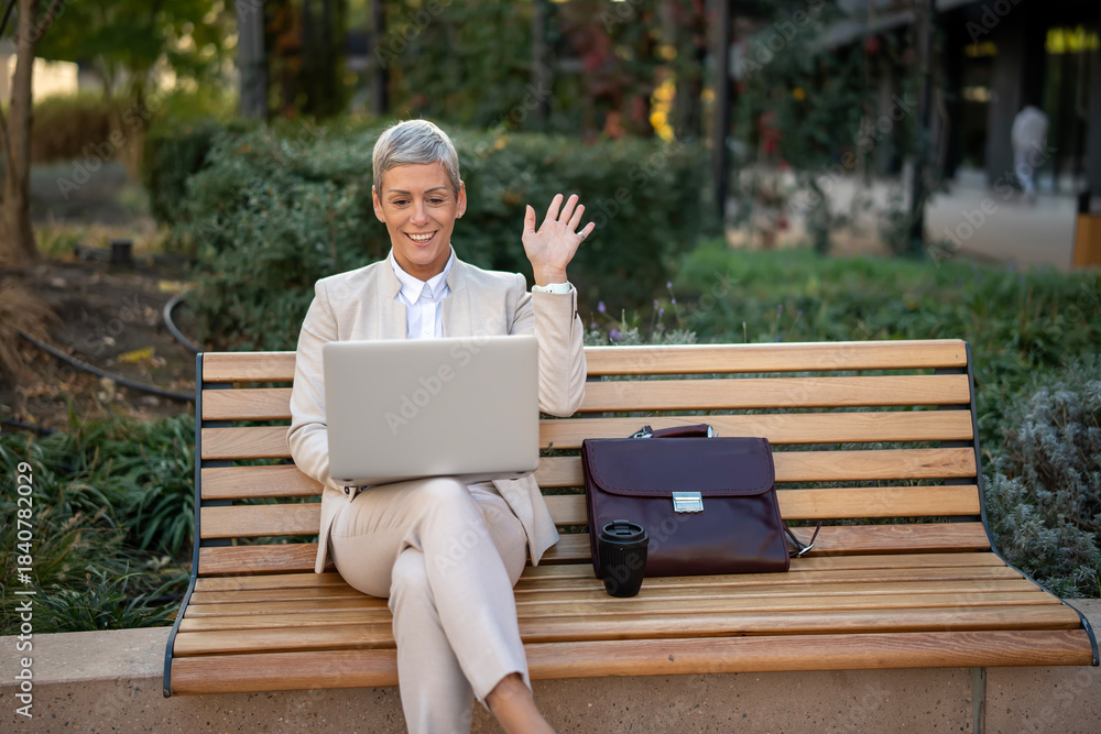 Fototapeta premium Mature businesswoman having video call outdoors on laptop