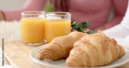 Camera shifting focus from orange juice glasses to brown croissants at home, highlighting textures