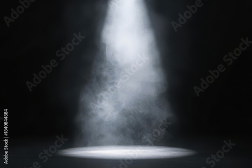 Bright spotlight shining down on a dark stage with smoke
