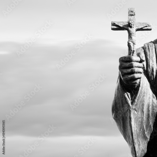 cross in hand of old statue as invitation to follow and have faith with plenty of space for copy and graphics
