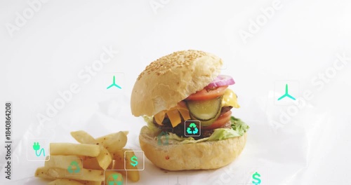 Top bun entering frame, burger with fries showing layers, teal icons appearing, showing eco value