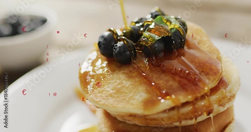 Golden syrup pouring from top-right, coating pancake stack and blueberries to create glossy glaze