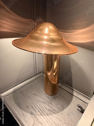 Industrial Copper Lighting: Close-up of a metal lamp fixture with warm wall reflections