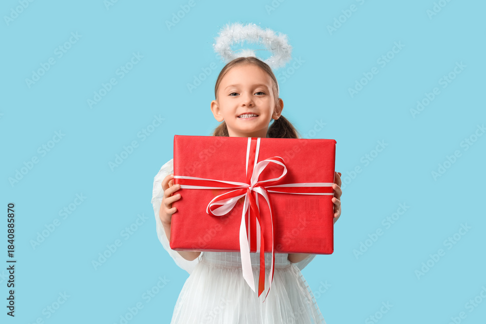 Obraz premium Cute little girl dressed as Cupid with gift box on blue background. Valentine's Day celebration