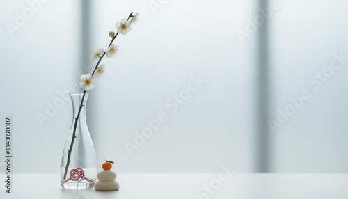 ガラス花瓶の白い梅の花と鏡餅飾りと水引のミニマルなお正月イメージ
