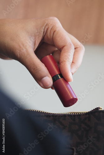 Vászonkép Hand holds lipstick tube in a bag during makeup touch-up