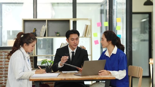 A lone Asian male doctor is working in a hospital conference room.