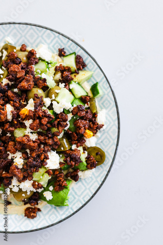 healthy nourish bowl with spicy vegan mince, avocado, olives, cucumber and hummus