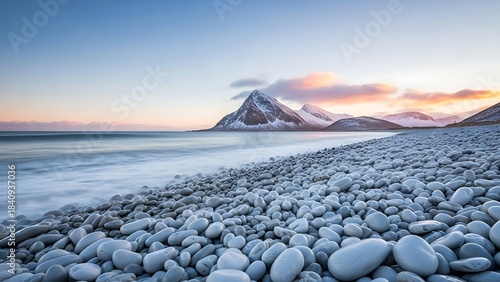 Fototapeta Naklejka Na Ścianę i Meble -  Serene landscape of snow covered mountains and rocky beach at sunset with calm sea and vibrant sky