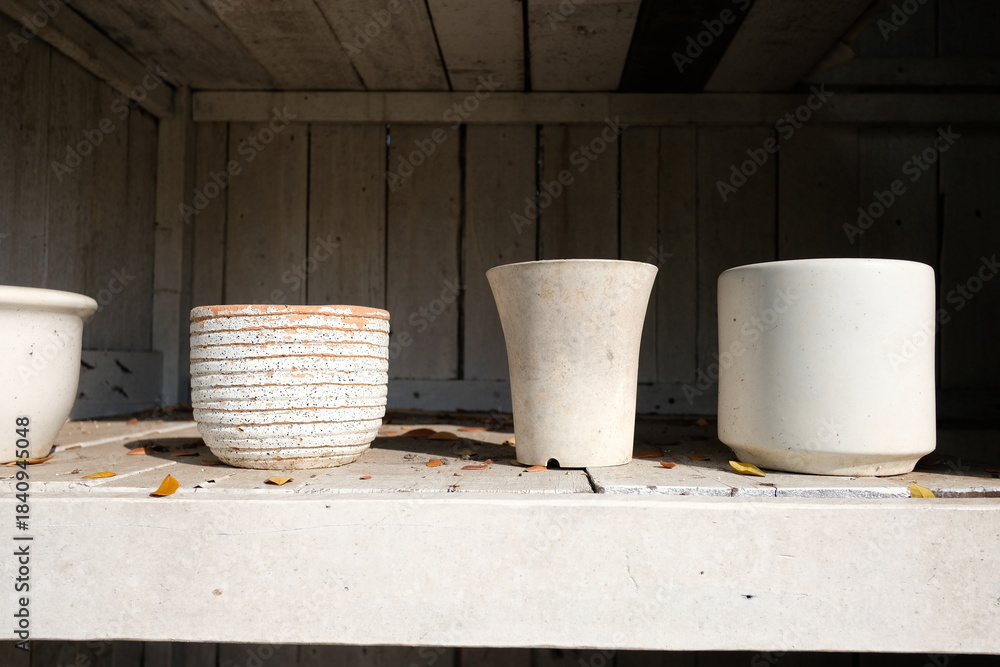 Naklejka premium Rustic planters on a weathered shelf in natural sunlight