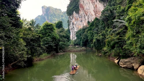 Discover the stunning landscapes of Khao Sok National Park in Thailand. a couple on a traditional bamboo raft on the river in thailand in the green jungle with huge cliffs