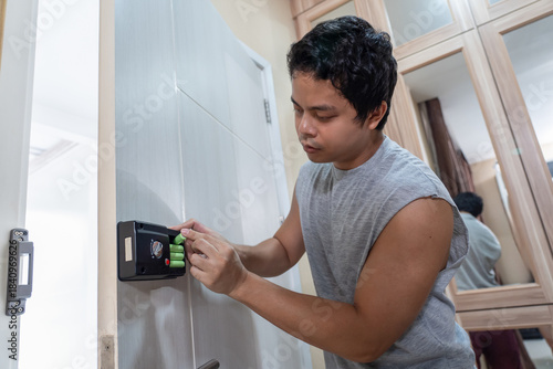 Man technician installs digital door lock on the wood door.