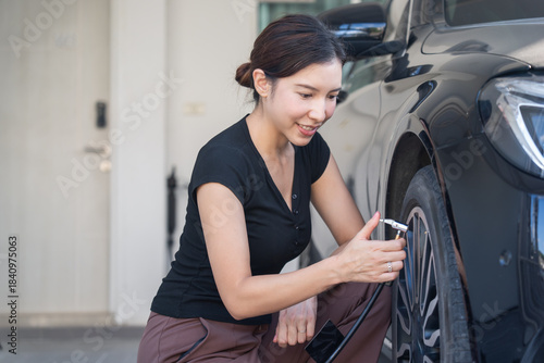 Woan mechanic inflating tire and checks air pressure with a pressure.