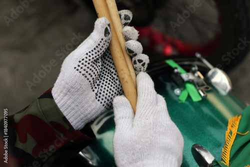 the musician plays the drums. A hand wearing a white glove firmly holds a wooden stick with precision and control