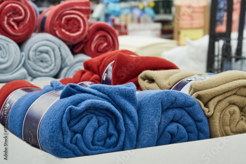 Multicolored warm blankets rolled into a roll are sold in the store.