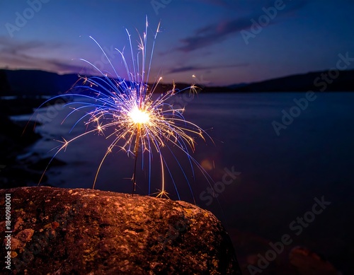 Glowing sparkler ignites against a twilight lake and mountain backdrop