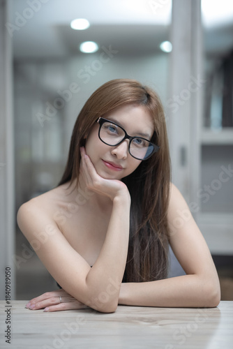 Woman wearing black underwear and glasses pose in the bedroom.