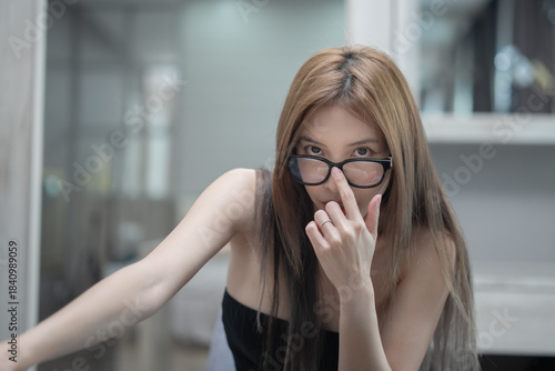 Woman wearing black underwear and glasses pose in the bedroom.