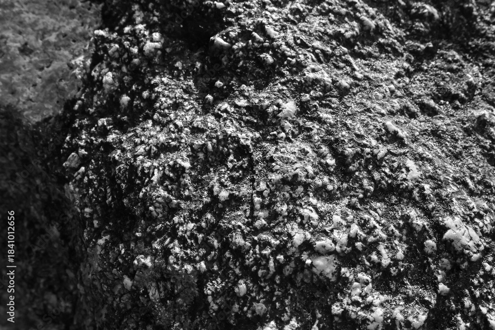 Obraz premium Rough stone surface texture background in black and white. This natural abstract rock pattern shows close up of gray mineral with gritty, rugged detail for geology