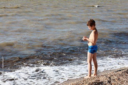 Boy at shoreline playing with sand
