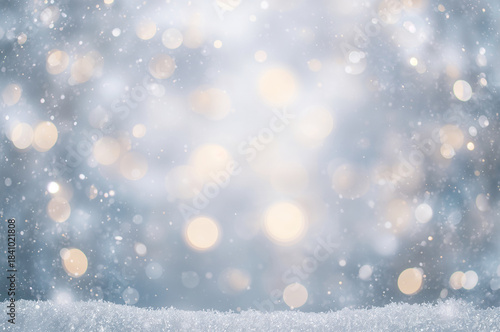 Abstract winter background featuring soft, shimmering golden and white bokeh lights, falling snow, and a foreground of sparkling snow.