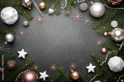 Sophisticated flat lay with rose gold, silver, and geometric ornaments on a charcoal background, framed by dark green pine branches. copy space