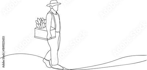 Man in hat carrying box of vegetables on a path overalls