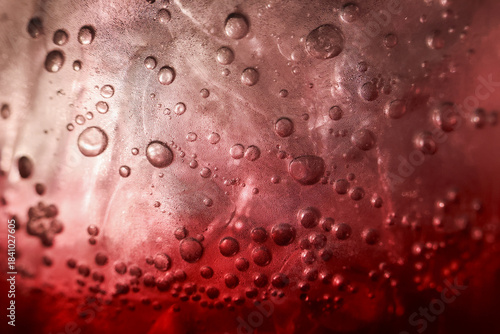 Tableau sur toile Refreshing closeup of cold red beverage with an ice cube and carbonated bubble